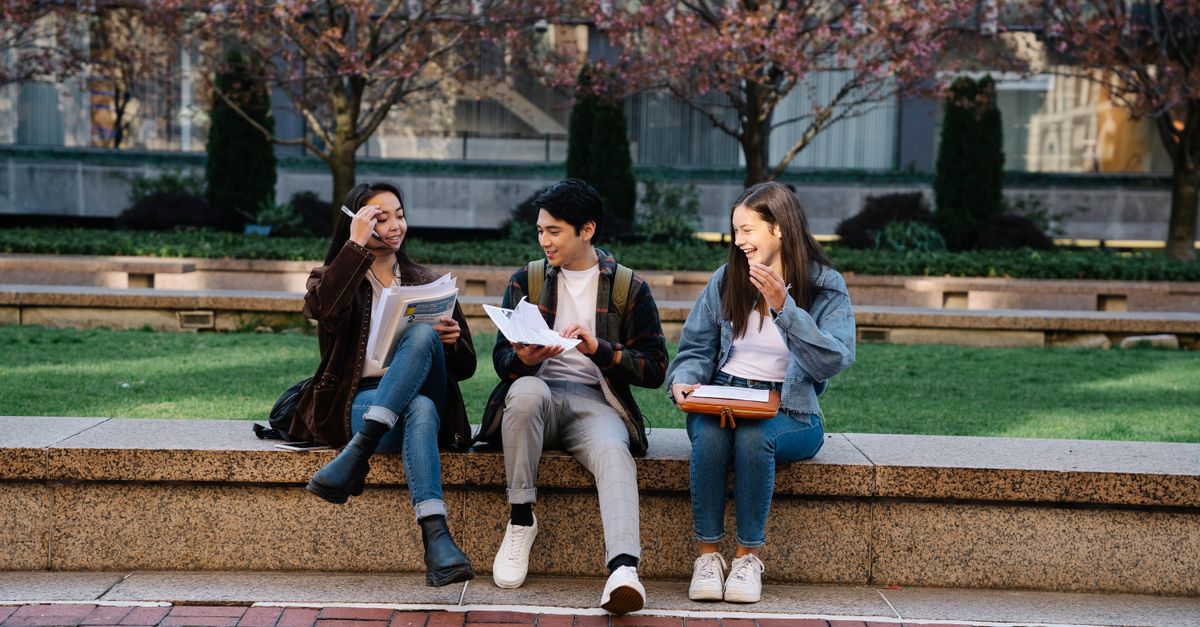 Students walking across a British university campus on a bright day